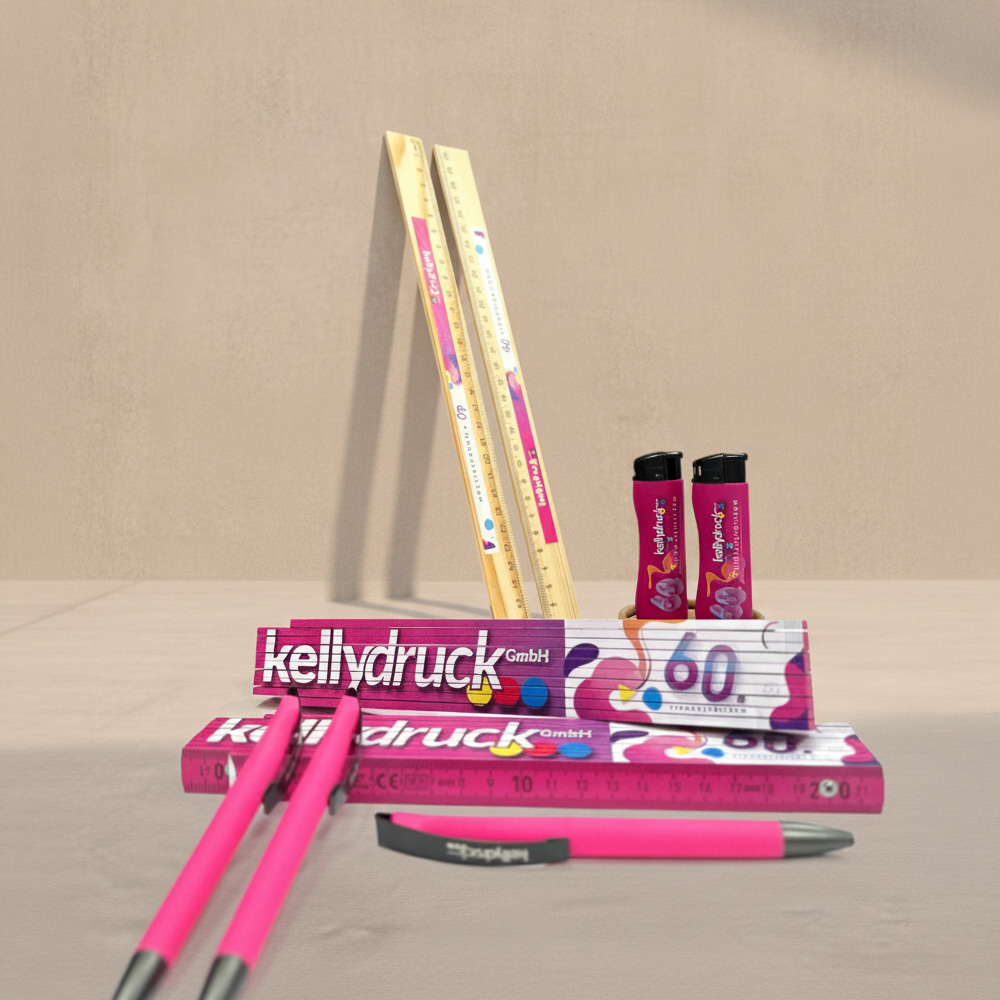 Geschaefftsausstattung_Kelly_Druck Eine Zusammenstellung von Werbeartikeln für das 60. Jährige Jubiläum der Firma Kelly Druck bestehend aus zwei Holzlineale, zwei pinke Feuerzeuge mit schwarzem Kopf, zwei Meterstäbe mit einer großen Abbildung des Logos von "Kelly Druck" in pink und daneben 3 pinke Kugelschreiber.